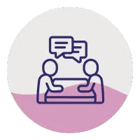 Icon of two people sitting at a table having a conversation, shown by speech bubbles above their heads. The graphic is within a circle with a purple and white background.
